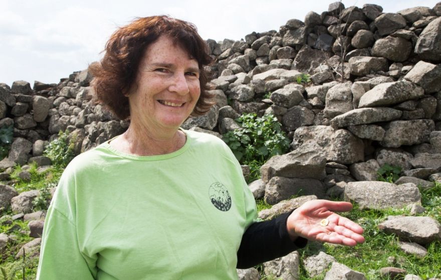 Laurie Rimon with the coin. (Samuel Magal, courtesy of the Israel Antiquities Authority)